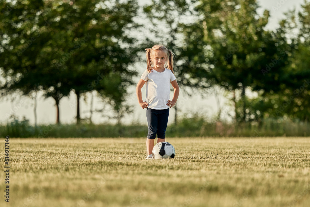 Girl with hand on hip standing by soccer ball at sports field Girl with hand on hip standing by soccer ball at sports field