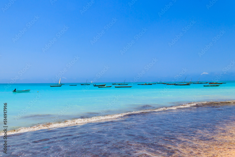 View of tropical sandy Nungwi beach and traditional wooden dhow boats in the Indian ocean on Zanzibar, Tanzania View of tropical sandy Nungwi beach and traditional wooden dhow boats in the Indian ocean on Zanzibar, Tanzania