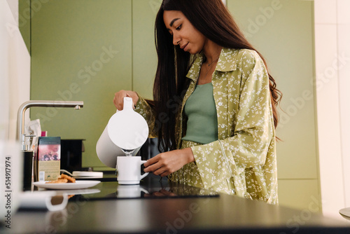 Young beautiful long-haired woman pouring hot water into a cup