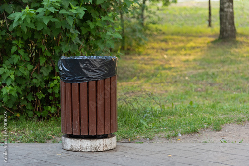 Obraz na płótnie A wooden trash can stands in a green park on the sidewalk w salonie