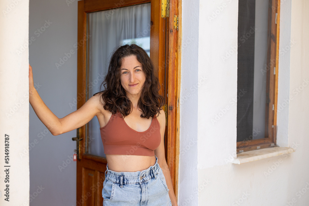 A girl in shorts and a top stands near the door of a wooden house A girl in shorts and a top stands near the door of a wooden house