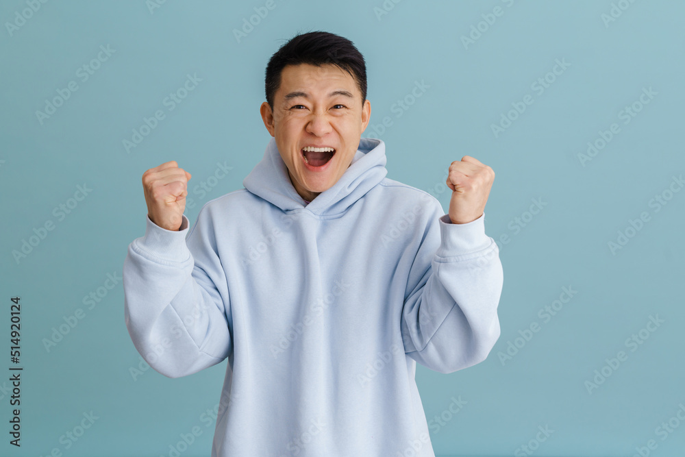 Brunette adult asian man screaming in joy and clenching his fists Brunette adult asian man screaming in joy and clenching his fists