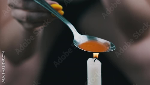 Woman drug addict cooking drugs in spoon on candle flame. Warming narcotic fluid over fire by bringing it to boiling and bubbling. Crop junkie preparing heroin dose. Hard narcotic substance. Close-up photo