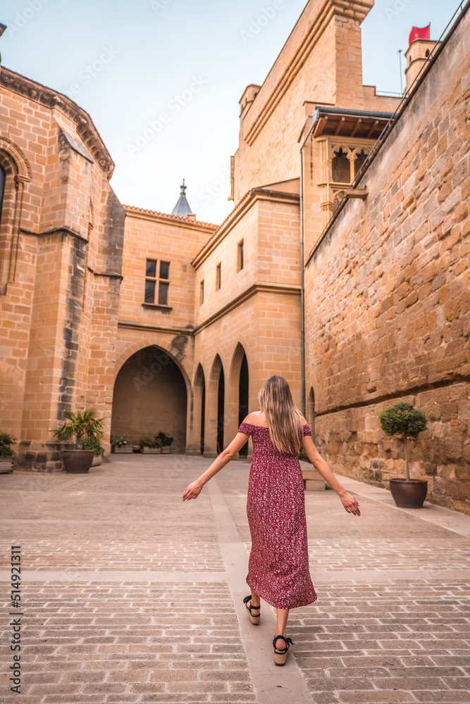 Blonde girl walking in a medieval castle, enjoying the holidays