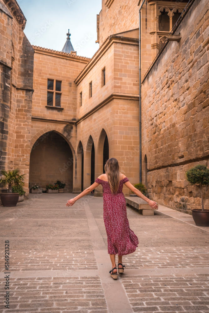 Blonde girl walking in a medieval castle, walking towards the entrance