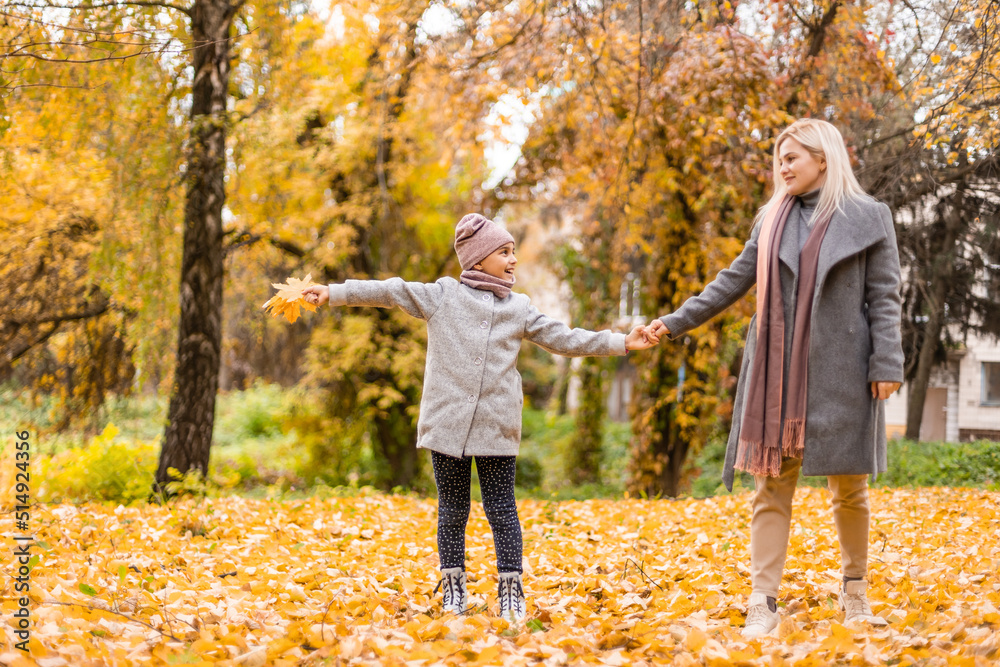 Fototapeta premium Mother and daughter in autumn yellow park.