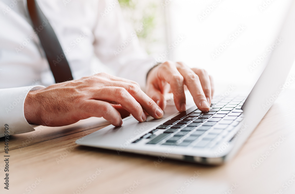 Businessman using laptop computer, hands typing keyboard at office desk Businessman using laptop computer, hands typing keyboard at office desk