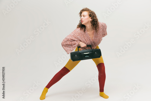 Portrait of young beautiful astonished girl in avant-garde style over white background. Vivid style, beauty, queer, freak, fashion concept. photo