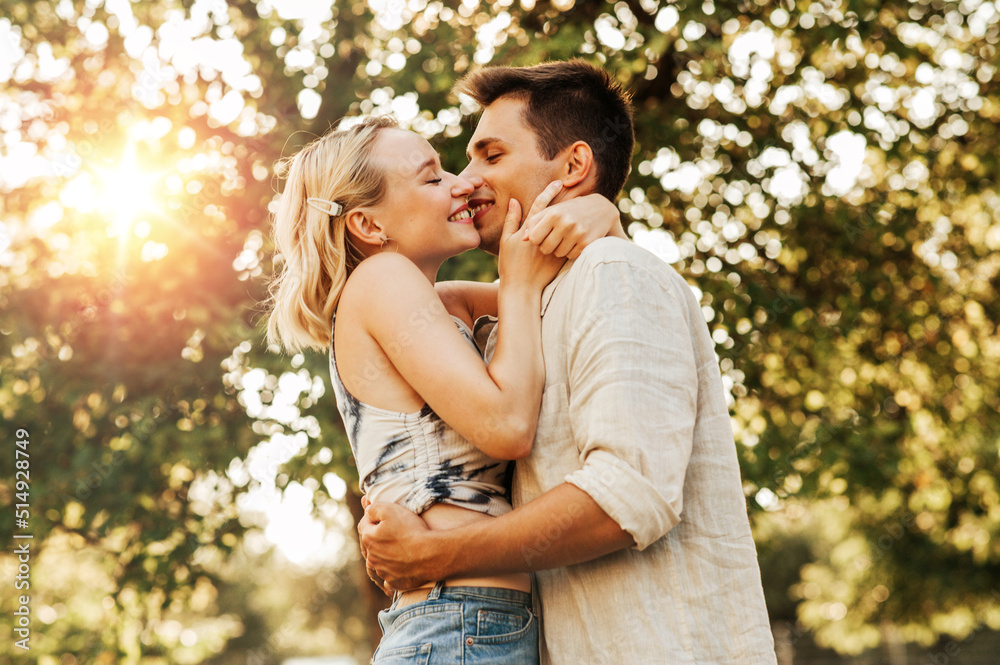 summer holidays, love and people concept - happy young couple kissing and hugging outdoors summer holidays, love and people concept - happy young couple kissing and hugging outdoors
