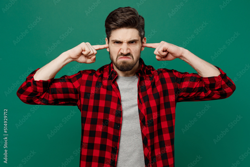 Young sad caucasian man he 20s wear red shirt grey t-shirt cover ears with hands fingers do not want to listen scream isolated on plain dark green background studio portrait People lifestyle concept. Young sad caucasian man he 20s wear red shirt grey t-shirt cover ears with hands fingers do not want to listen scream isolated on plain dark green background studio portrait People lifestyle concept.