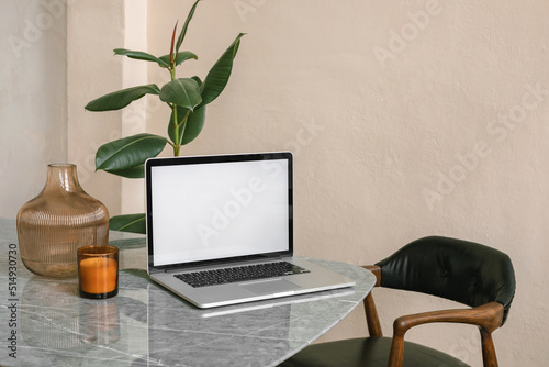 Modern minimalistic office interior. Laptop with blank screen on table.