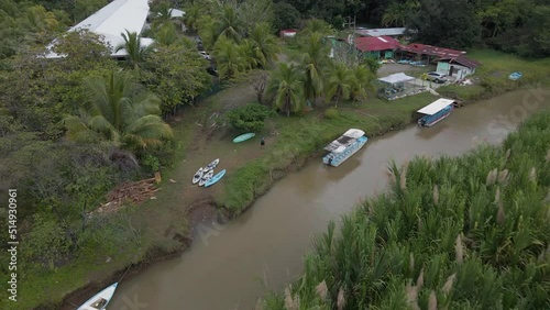 Man standing between kayaks and boats at the shore of rio cotos near Manuel Antonio, Costa Rica. Aerial tilting pull away shot photo