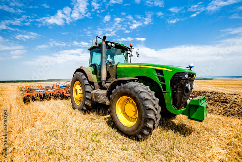 Tractor working in wheat field. Agriculture background. Harvest season