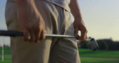 Golfer hands holding putter on sunset course field. Man enjoy golf outdoors.