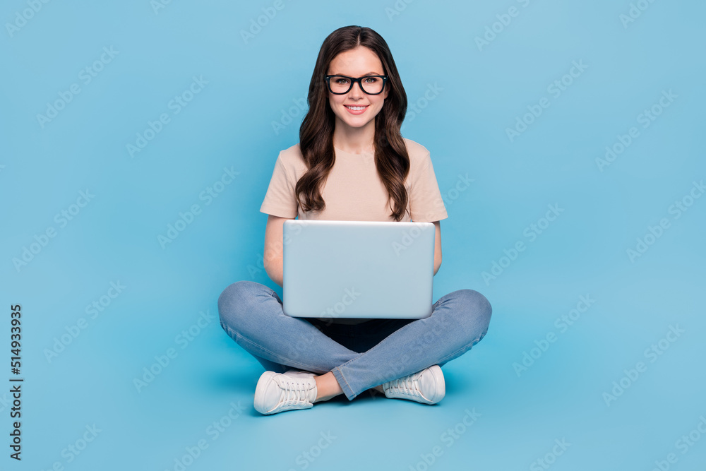 Full length photo of lady use netbook typing email clients partners wear t-shirt jeans isolated blue color background Full length photo of lady use netbook typing email clients partners wear t-shirt jeans isolated blue color background