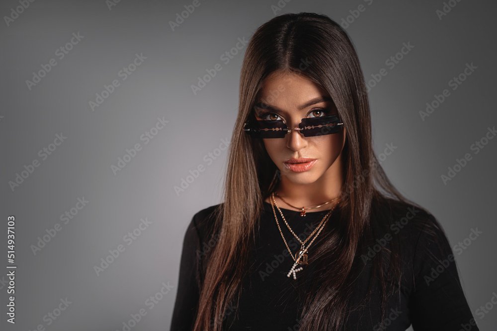 Beautiful young lady in a black turtleneck with massive jewelry and extraordinary sunglasses. Refined taste. Elegance. Sexy. Copy space Beautiful young lady in a black turtleneck with massive jewelry and extraordinary sunglasses. Refined taste. Elegance. Sexy. Copy space