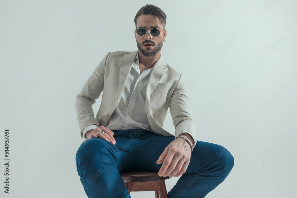 sexy man with open collar shirt and glasses holding elbow on knees sexy man with open collar shirt and glasses holding elbow on knees