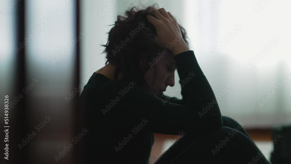 Depressed woman sitting on floor covering face with hands in despair