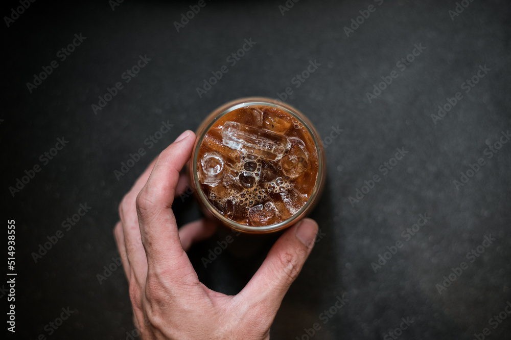 hand holding a take-out iced coffee on black table hand holding a take-out iced coffee on black table