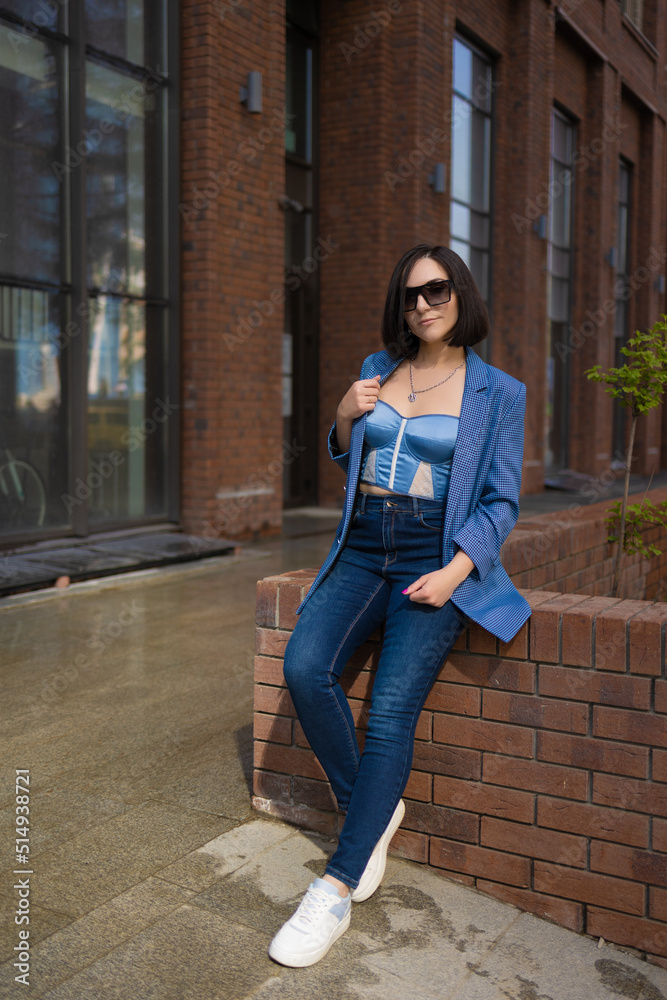 brunette girl in a blue jacket and jeans walks through the city streets