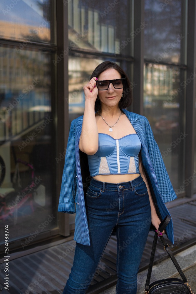 brunette girl in a blue jacket and jeans walks through the city streets