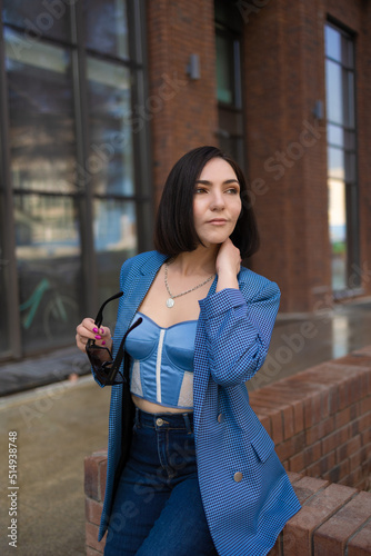 brunette girl in a blue jacket and jeans walks through the city streets © Анна Минина