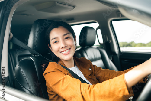 Young beautiful asian women getting new car. she very happy and excited. Smiling female driving vehicle on the road on a bright day. © Chanakon