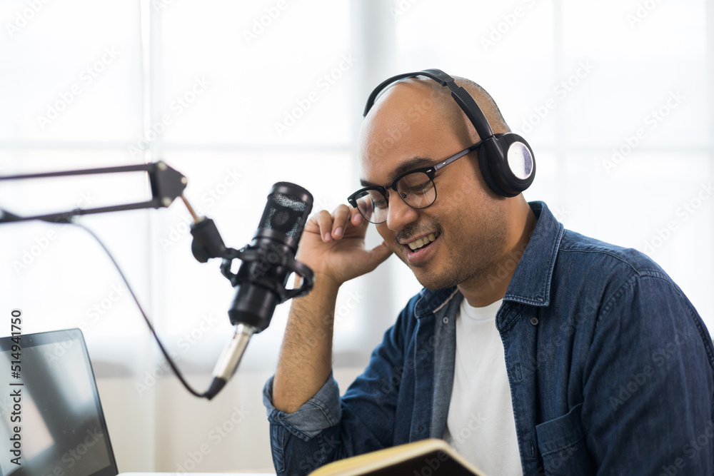 Content creator asia man host streaming his a podcast on laptop with headphones and condenser microphone interview guest conversation at home broadcast studio. Male blogger recording voice over radio Content creator asia man host streaming his a podcast on laptop with headphones and condenser microphone interview guest conversation at home broadcast studio. Male blogger recording voice over radio