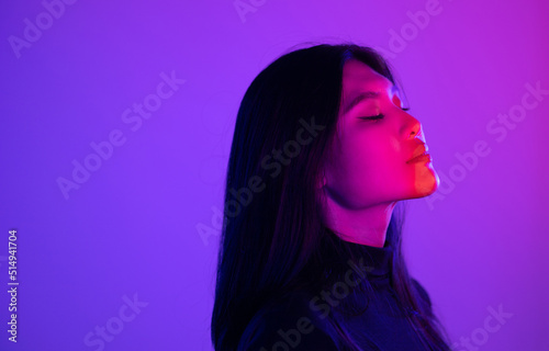 Stylish sexy woman in trendy. Beautiful young asian woman standing pose with neon light. Asia Pretty asian female in the dark room. Fashion shot.