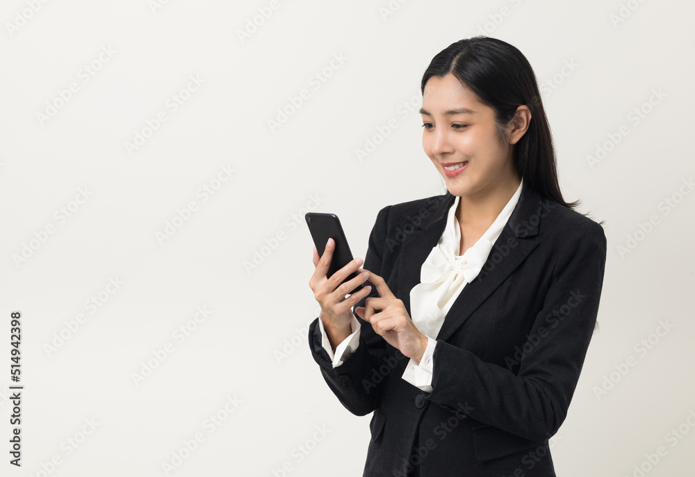 Happy young asian business woman using smartphone on isolated white background. Attractive female in suit holding cell phone feeling happy. Portrait shot in studio. Happy young asian business woman using smartphone on isolated white background. Attractive female in suit holding cell phone feeling happy. Portrait shot in studio.