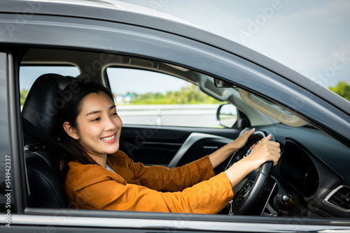 Young beautiful asian women getting new car. she very happy and excited. Smiling female driving vehicle on the road on a bright day. © Chanakon