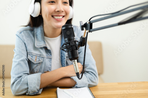 Content creator woman host streaming her a podcast on laptop with headphones and microphone interview cheering guest conversation at broadcast studio. Blogger motivation recording voice over radio.