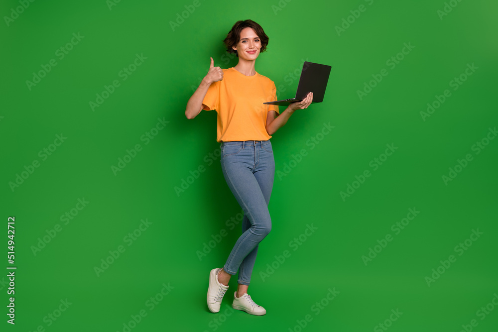 Full length portrait of nice attractive girl hold netbook demonstrate thumb up approve isolated on green color background Full length portrait of nice attractive girl hold netbook demonstrate thumb up approve isolated on green color background