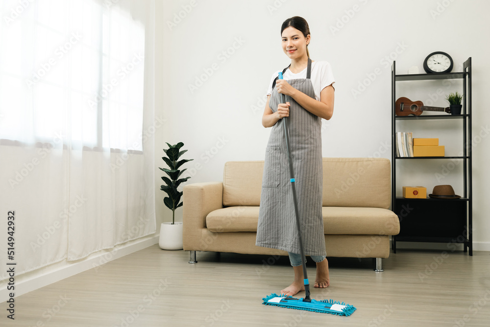 Young beautiful woman with apron and rubber glove with mop ready for cleaning home. Housekeeping housework or maid worker holding mop cleaning floor Young beautiful woman with apron and rubber glove with mop ready for cleaning home. Housekeeping housework or maid worker holding mop cleaning floor