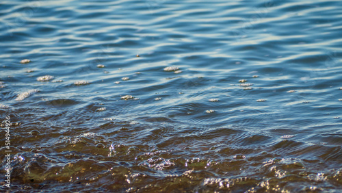 Texture of the background of seawater near the shore. The surface of the seawater near the shore as an abstract background. Abstract background of rippling waves in ocean water