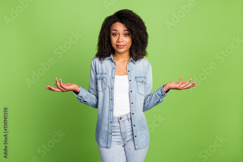 Photo of young pretty woman shrug shoulders puzzled uncertain doubts isolated over green color background photo
