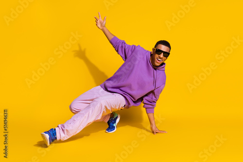 Full length body size view of attractive cheerful guy dancing low brake clubbing isolated over bright yellow color background