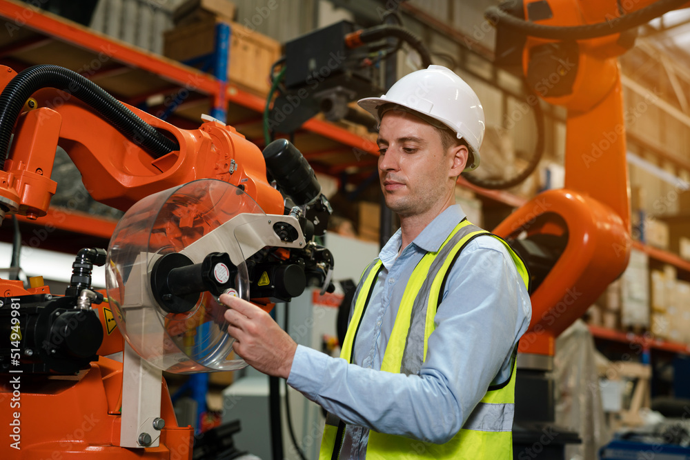 Male engineer checking and inspection control a robot arm machine welding steel in an industrial factory, Fast and highly secure.