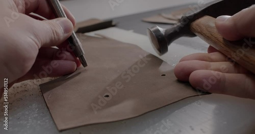 Close up view of master makes holes in leather piece to make shoes in 4k resolution