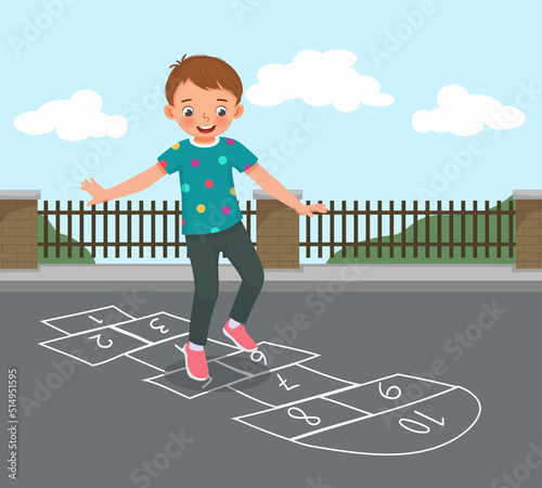 cute little boy playing hopscotch drawn with chalk outside on playground street at the park