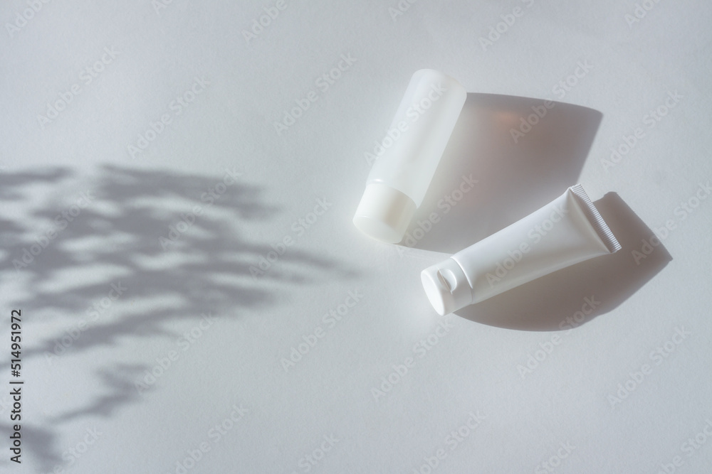 Cosmetic bottles with leaf shadow on white wall background Cosmetic bottles with leaf shadow on white wall background