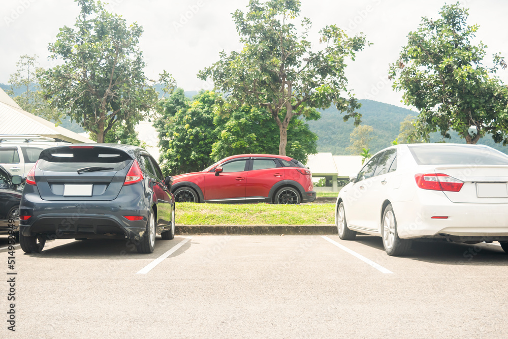 Car parked in asphalt parking lot and one empty space parking  in nature with trees, beautiful cloudy sky and mountain background .Outdoor parking lot with fresh ozone and green environment concept