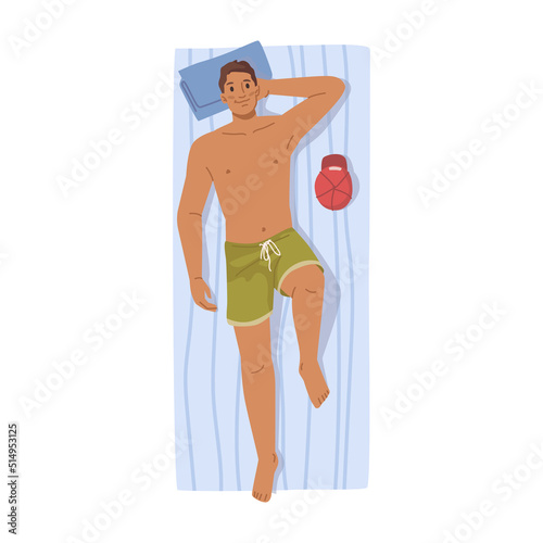 Man relaxing, handsome person lying on towel and sunbathing on sun, man in short lie on pillow at sun bath mat, hat near him. Top view of young man relax at beach