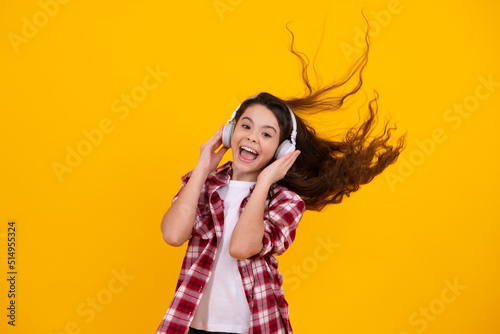 Amazed teenager. Child music concept. Teenager child girl dances in rhythm of melody, listens song in headphones. Child listening to music through earphones. Excited teen girl.