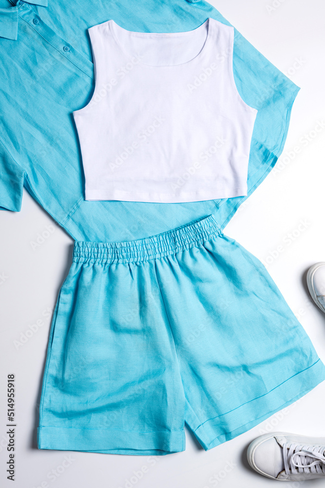 Still life of women's clothing: blue suit with shorts, shoes, top view layout Still life of women's clothing: blue suit with shorts, shoes, top view layout