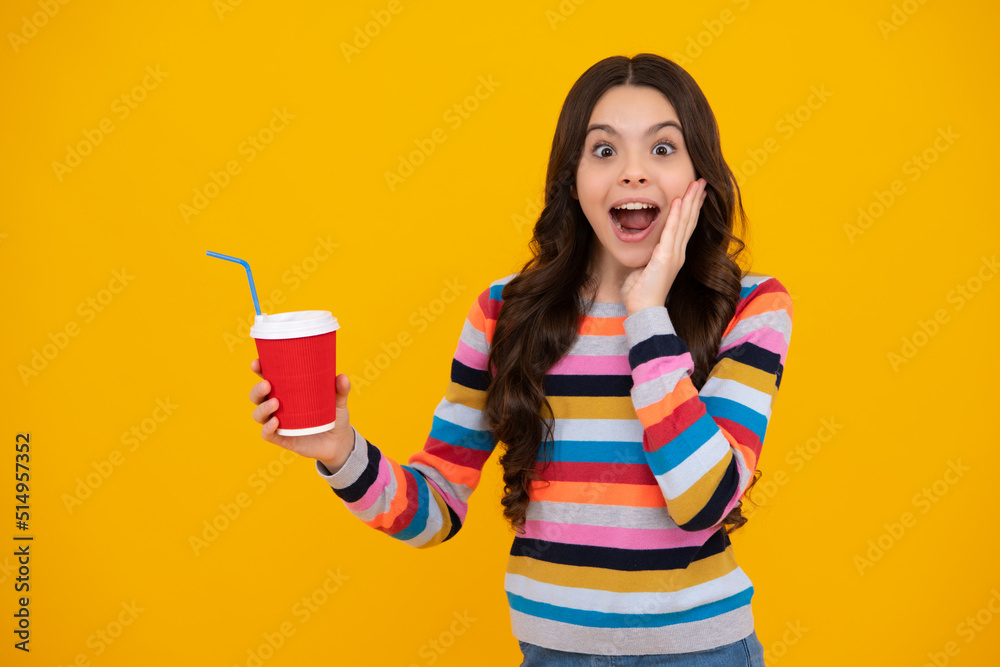 Amazed teenager. Teenager girl holding a hot cup of coffee or tea. Child with takeaway cup on yellow background, morning energy drink beverage. Excited teen girl. Amazed teenager. Teenager girl holding a hot cup of coffee or tea. Child with takeaway cup on yellow background, morning energy drink beverage. Excited teen girl.