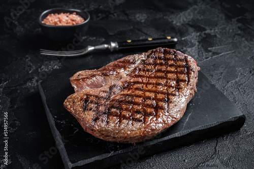 Grilled top sirloin or rump steak on a marble board. Black background. Top view
