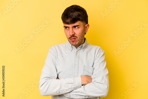 Young caucasian man isolated on yellow background tired of a repetitive task.