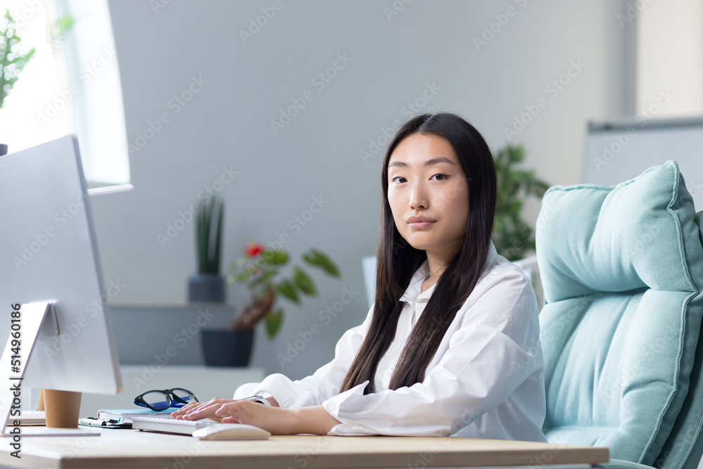 Portrait of successful Asian office worker woman, business woman working at computer looking at camera. Portrait of successful Asian office worker woman, business woman working at computer looking at camera.