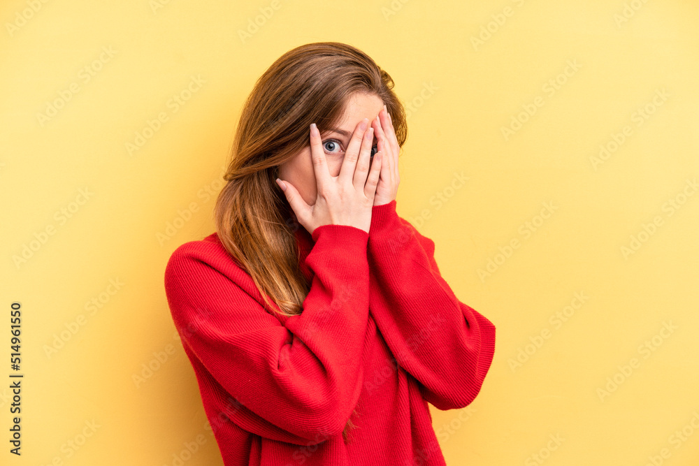 Young caucasian woman isolated on yellow background blink through fingers frightened and nervous. Young caucasian woman isolated on yellow background blink through fingers frightened and nervous.